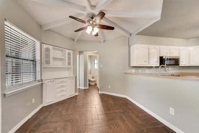 Kitchen featuring beamed ceiling, light countertops, ceiling fan, white cabinets, and stainless steel microwave