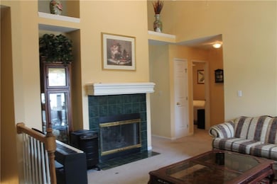 Carpeted living room featuring a fireplace and a towering ceiling