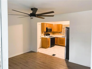 Kitchen with light countertops, appliances with stainless steel finishes, brown cabinetry, light wood-type flooring, and ceiling fan