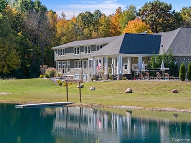 Back of property with a lawn, a water view, and roof with shingles
