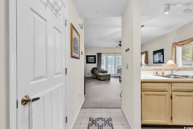 Corridor featuring plenty of natural light, light tile patterned floors, and light colored carpet