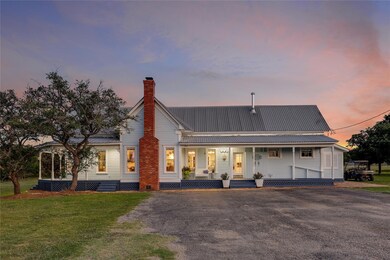 Back of property at dusk with covered porch, asph