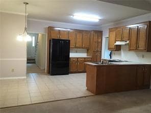 Kitchen with black refrigerator, a peninsula, hang