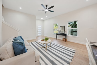 Living area with recessed lighting, light wood finished floors, ceiling fan, and stairway