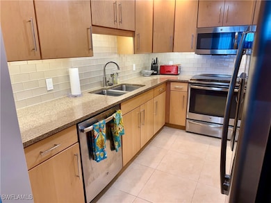 Kitchen featuring tasteful backsplash, light stone counters, stainless steel appliances, and light brown cabinets