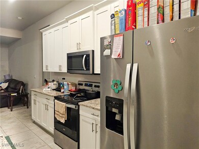 Kitchen featuring white cabinets, light stone coun