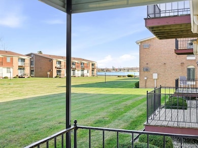 View of green lawn with a balcony and a water view