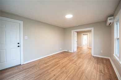 Empty room featuring a wall unit AC, light wood-st