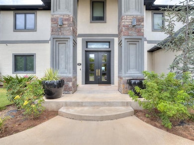 Doorway to property featuring stone siding, stucco siding, and french doors