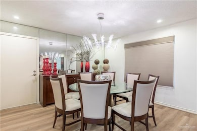 Dining area with a chandelier, light wood-style flooring, recessed lighting, and a textured ceiling