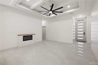 Unfurnished living room with visible vents, a ceiling fan, coffered ceiling, a glass covered fireplace, and light tile patterned flooring
