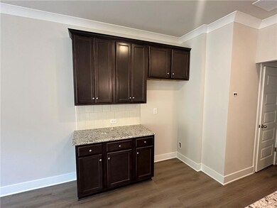 Bar area featuring dark wood-style flooring, baseboards, backsplash, and ornamental molding