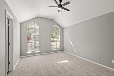 Empty room featuring lofted ceiling, carpet, baseb