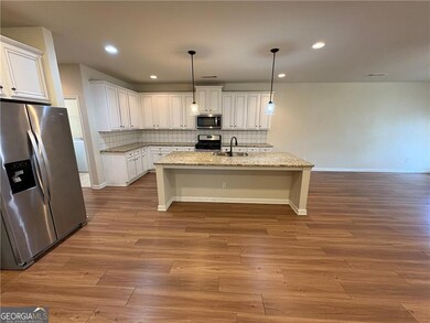 Kitchen featuring stainless steel appliances, a sink, tasteful backsplash, white cabinets, and an island with sink