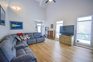 Living area with light wood finished floors, a ceiling fan, and high vaulted ceiling