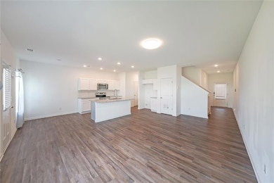 Kitchen featuring stainless steel appliances, dark wood-style flooring, white cabinetry, and open floor plan