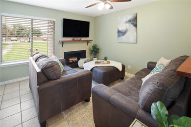 Living area featuring ceiling fan, a tiled firepla