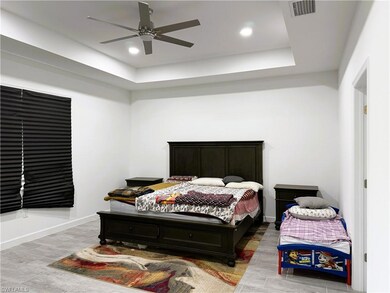 Bedroom featuring wood finished floors, a tray ceiling, recessed lighting, and ceiling fan