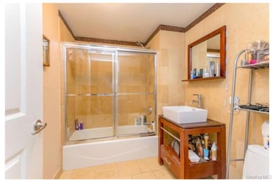 Bathroom with enclosed tub / shower combo, vanity, tile patterned flooring, and tile walls