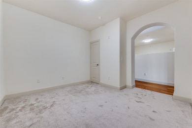 Spare room featuring arched walkways and light colored carpet