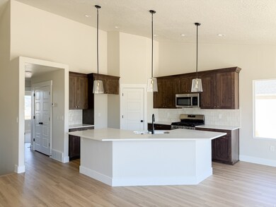 Kitchen with decorative backsplash, stainless steel appliances, high vaulted ceiling, light wood-style flooring, and decorative light fixtures