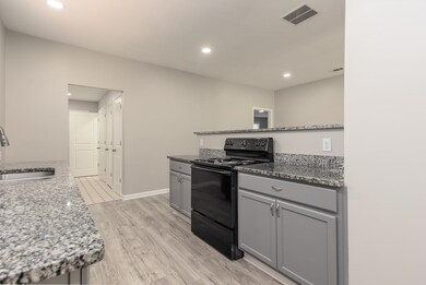 Kitchen with black electric range, light stone cou