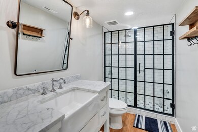 Full bath with a shower stall, toilet, vanity, and wood finished floors