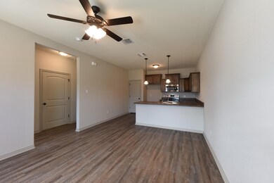 Kitchen with dark countertops, a peninsula, dark wood-style floors, and open floor plan