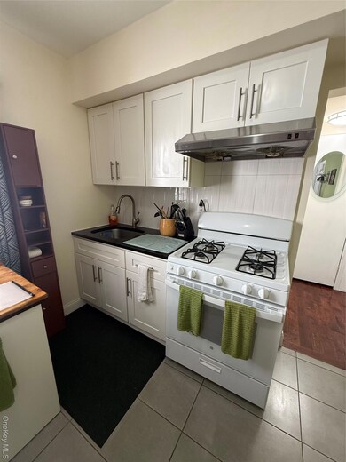 Kitchen with range, white cabinetry, dark tile patterned flooring, and exhaust hood