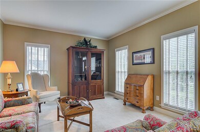 Another view of the living room showing crown molding and large windows for natural light.
