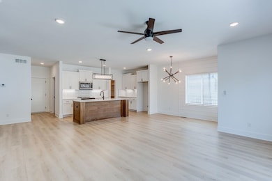 Kitchen with pendant lighting, light hardwood / wood-style flooring, and an island with sink