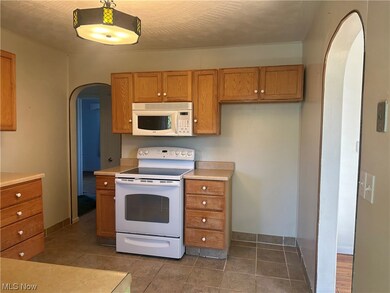 Kitchen featuring white appliances and dark tile flooring