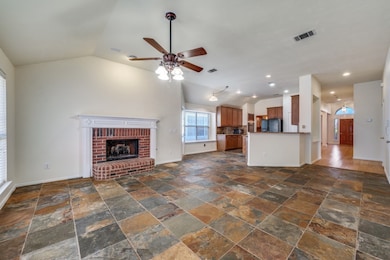 Unfurnished living room with lofted ceiling, a brick fireplace, stone tile flooring, ceiling fan, and recessed lighting