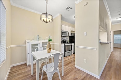 Dining space with crown molding, light wood-type 