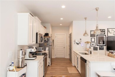 Kitchen featuring stainless steel appliances, light countertops, white cabinets, a sink, and recessed lighting