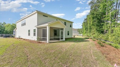 Back of property with a sunroom and a lawn