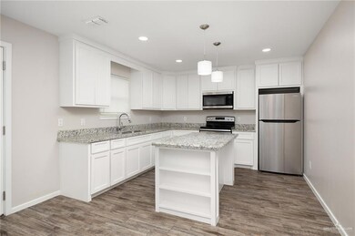 Kitchen with stainless steel appliances, open shelves, wood finished floors, a kitchen island, and white cabinets