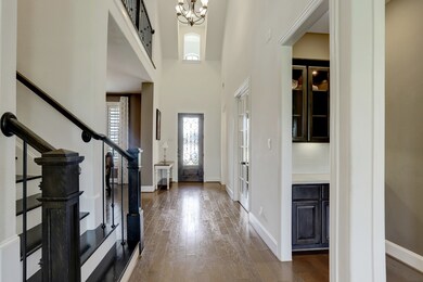 Stunning two story entry with soaring ceilings and iron spindle details. Dry bar to the right with subway tile backsplash.