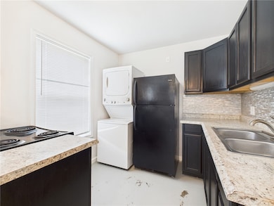 Kitchen with black appliances, stacked washer / dr