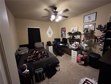 Bedroom with light colored carpet, ceiling fan, and a desk