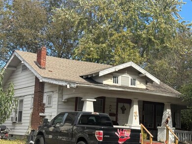 View of front of house with roof with shingles, a porch, and a chimney
