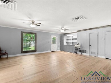 Unfurnished living room featuring a ceiling fan, crown molding, baseboards, light wood-style flooring, and a textured ceiling