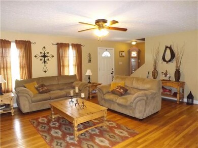 Living room with hardwood floors that continue through the kitchen, dining area and hallway