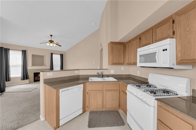 Kitchen featuring a sink, a peninsula, white appli