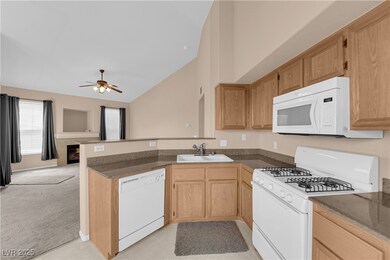 Kitchen featuring a sink, a peninsula, white appli