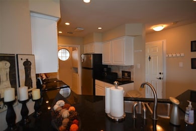 Kitchen with white cabinets, recessed lighting, and decorative backsplash