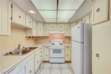 Kitchen featuring white appliances, light countertops, and under cabinet range hood