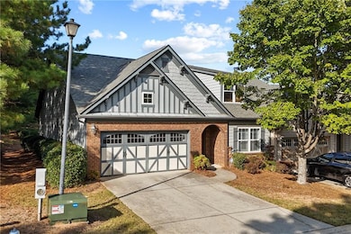 View of front of property featuring board and batten siding, roof with shingles, brick siding, and driveway
