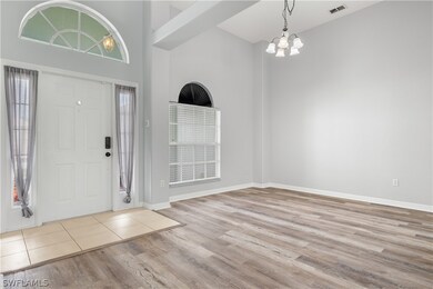 Entrance foyer featuring plenty of natural light, an inviting chandelier, light hardwood / wood-style floors, and a high ceiling