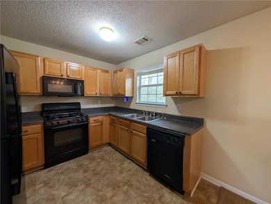 Kitchen featuring a sink, a textured ceiling, dark